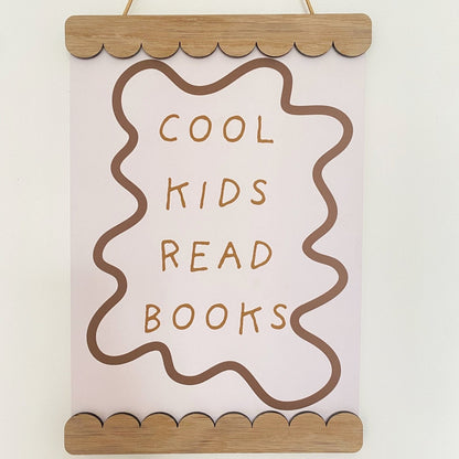 Decorative sign with 'Cool kids read books' text on a plain background