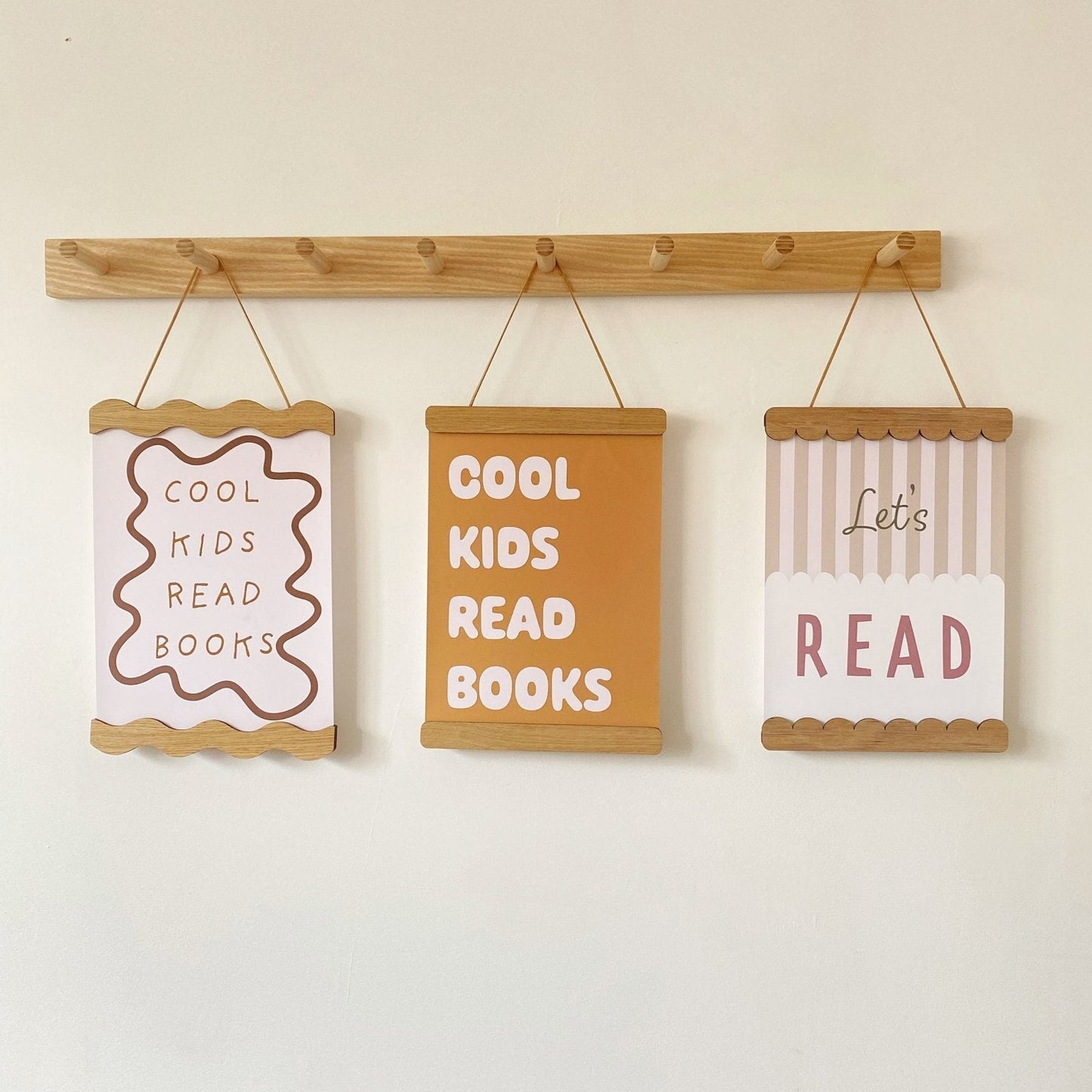 Three motivational signs hanging on a wooden rod against a white wall.