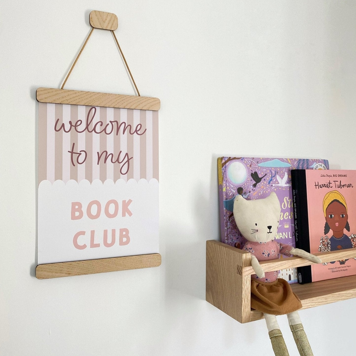 Wooden shelf with books and a plush toy, featuring a hanging sign that reads 'welcome to my Book Club'.