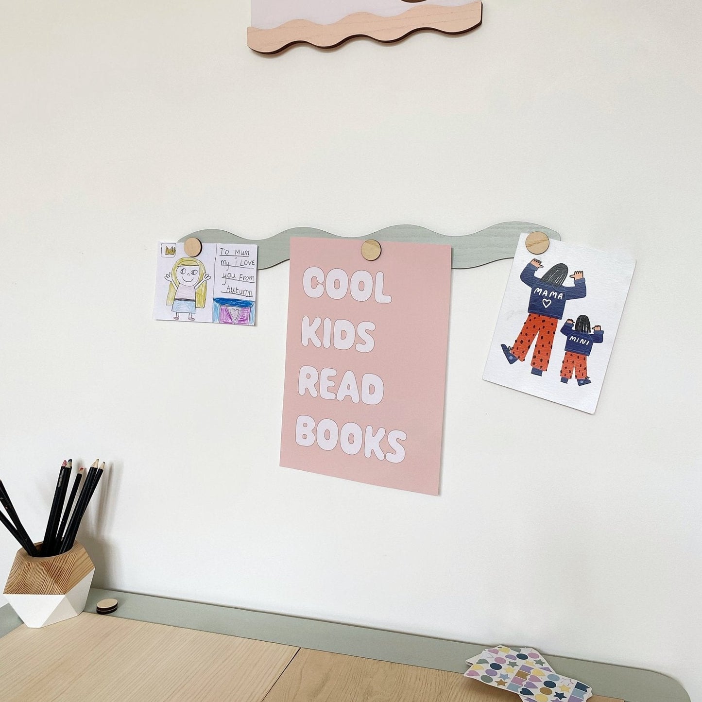 Wall with a 'book club' poster, 'Cool kids read books' poster, and children's drawings.