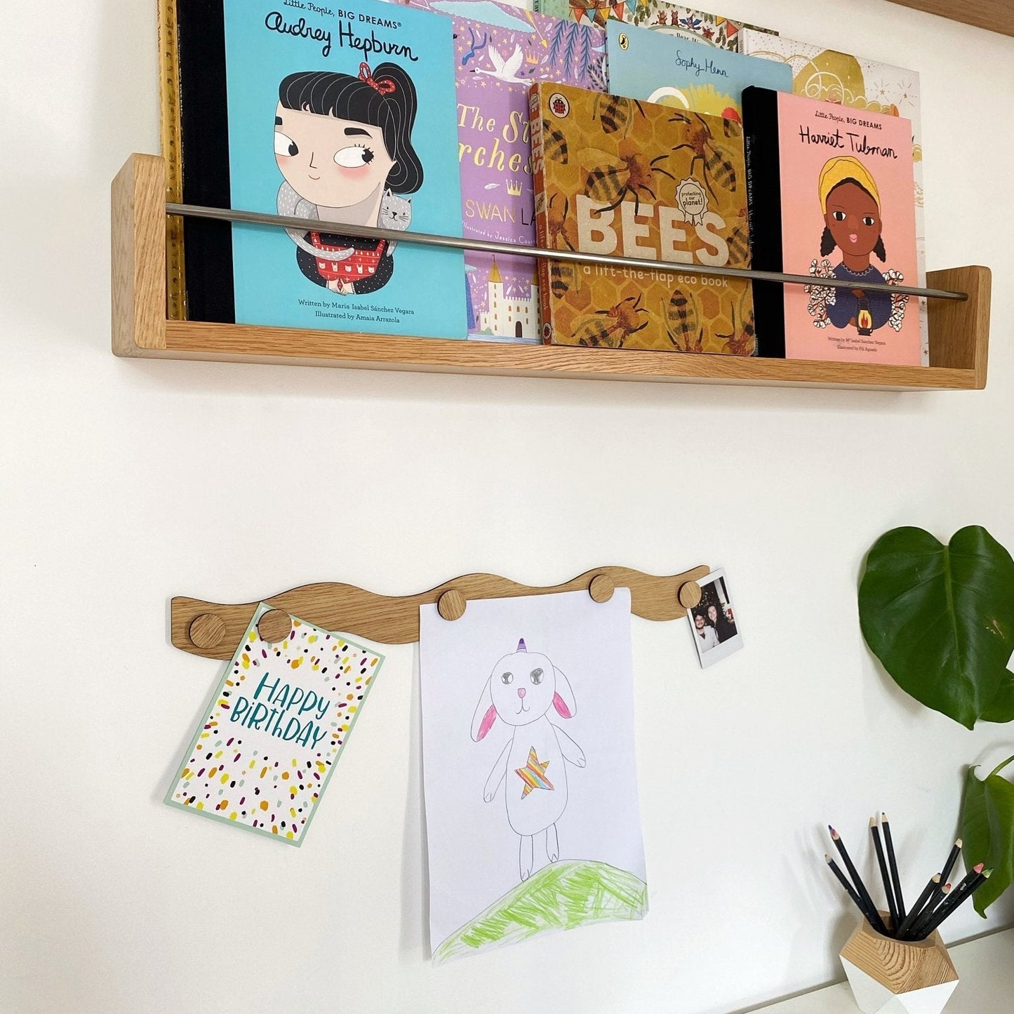 Wooden wall shelf with children's books and a calendar on a white wall.