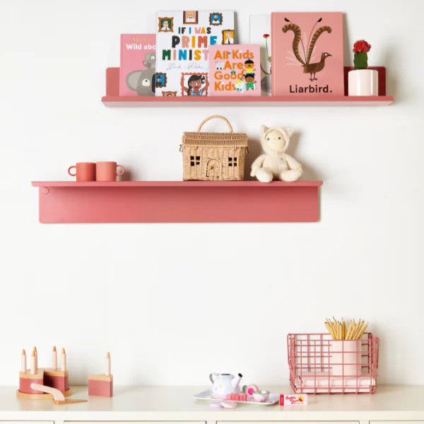 Pink shelves with toys and books against a white wall