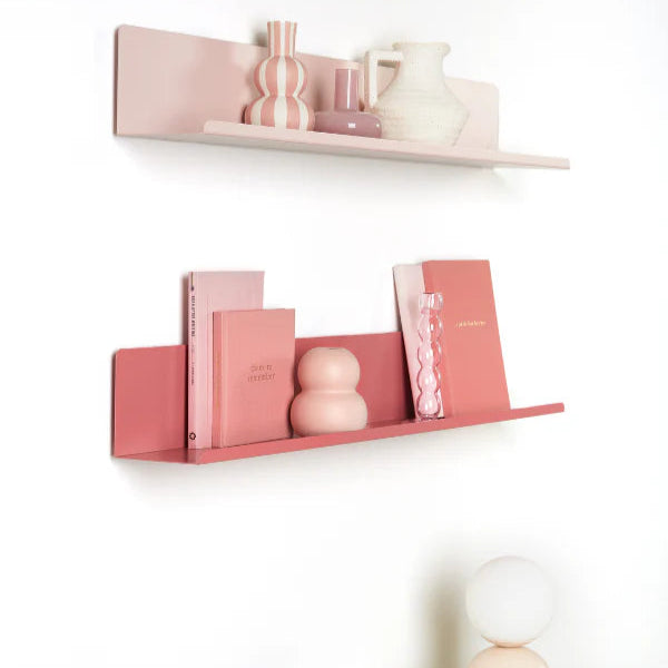 Pink and white shelves with decorative items on a white wall.