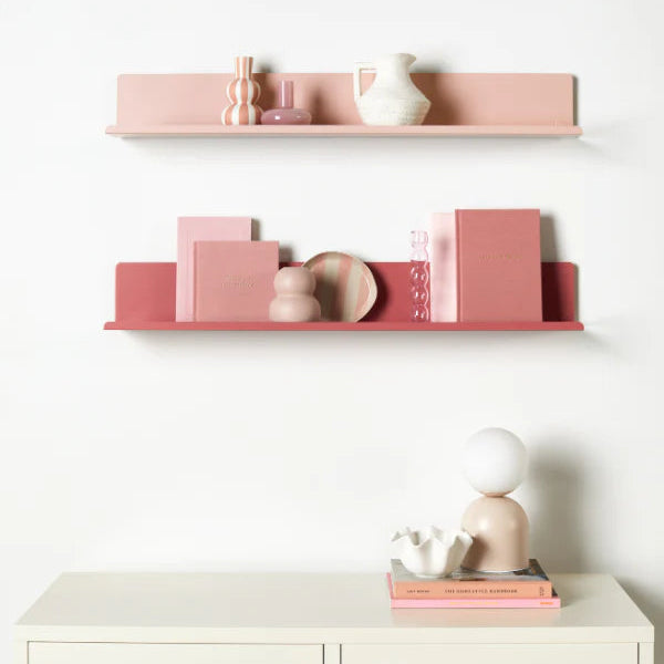 Pink shelves with decorative items against a white wall