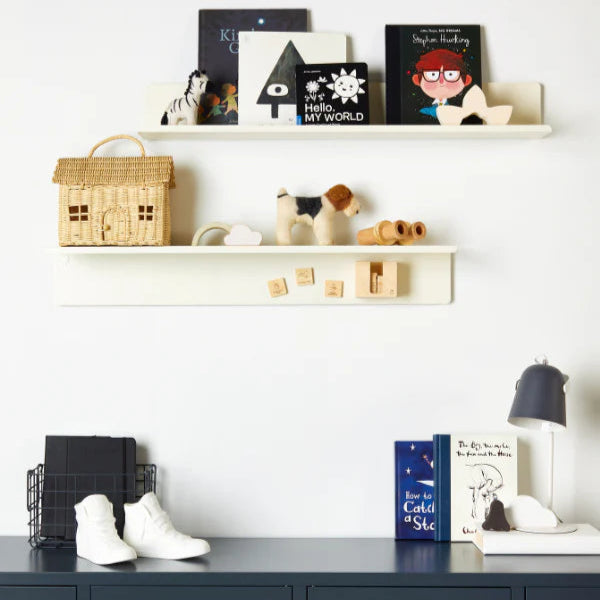 Nursery room with shelves displaying books, toys, and decorative items against a white wall.