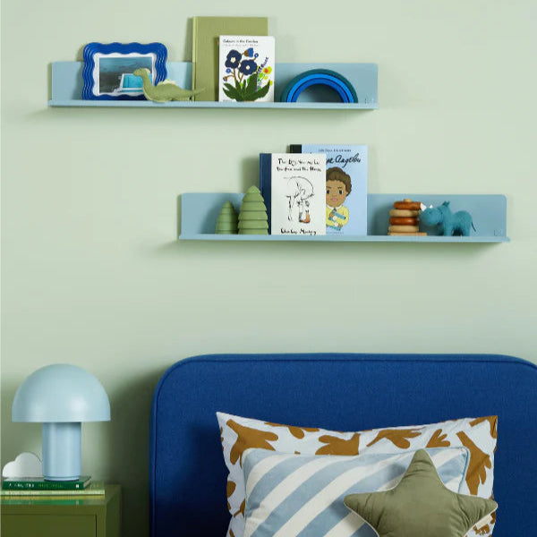 Children's room with blue bed, shelves with toys, and green wall.