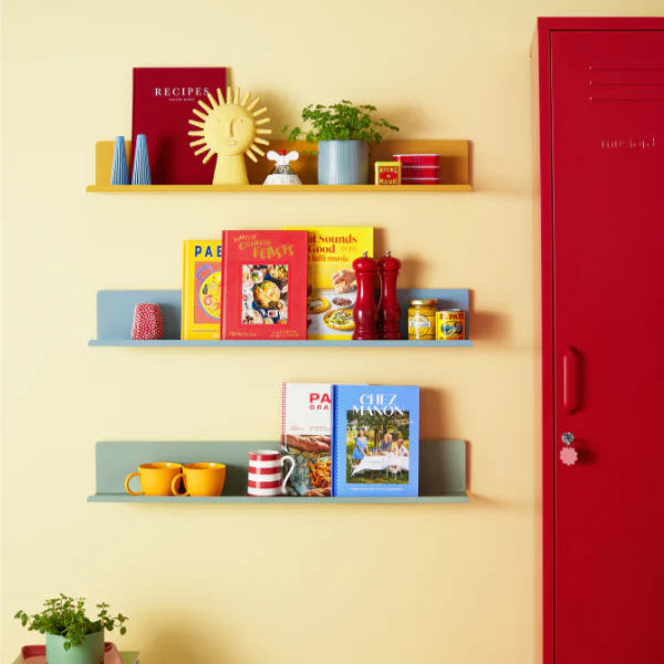 Shelves with books and decorative items against a yellow wall with a red door.