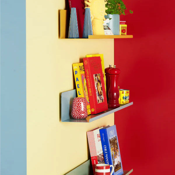 Colorful shelves against a red, yellow, and blue wall with books, mugs, and decorative items.