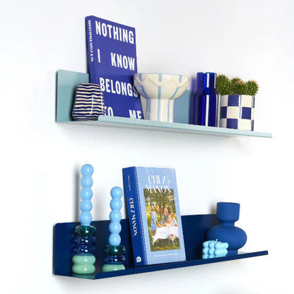 Decorative shelves with books, vases, and a lamp on a white wall.