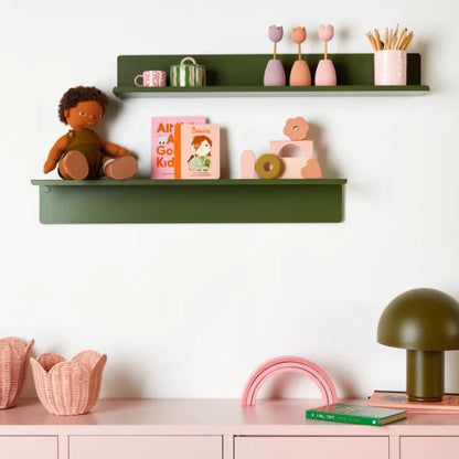 Children's room with green shelves and pink locker, featuring books and toys.