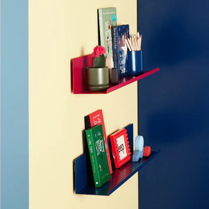 Colorful shelves against a multicolored wall with various items on them.