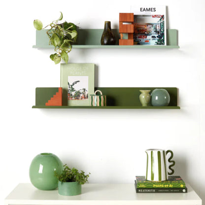 Decorative shelves with books, vases, and plants against a white wall.