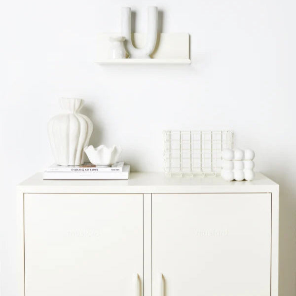 White cabinet with decorative items including a plant, basket, and bottles on a white background