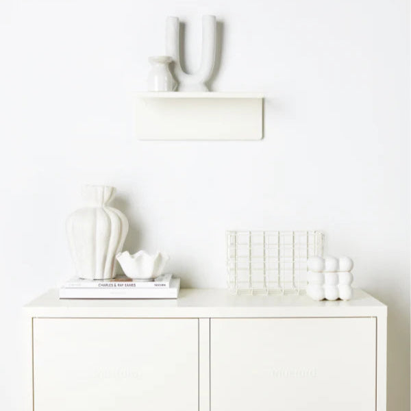 White cabinet with decorative items including a plant, basket, and bottles on a white background