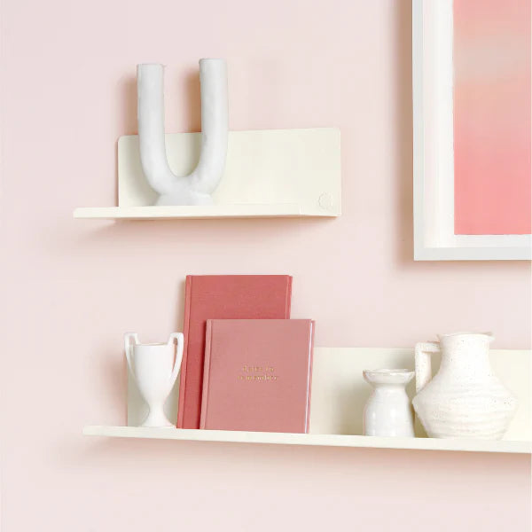 White cabinet with decorative items on a pink background