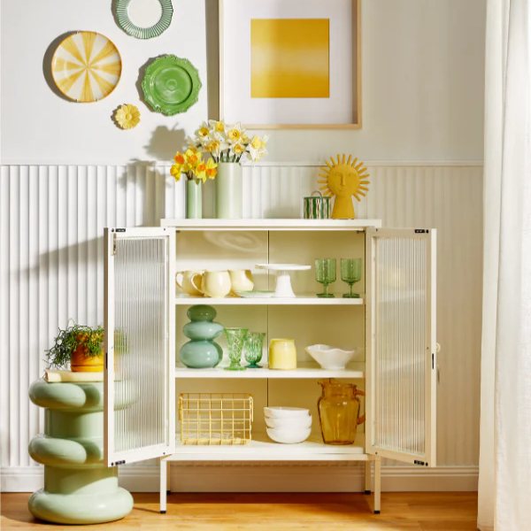 glass and metal cabinet door open with home decor inside.