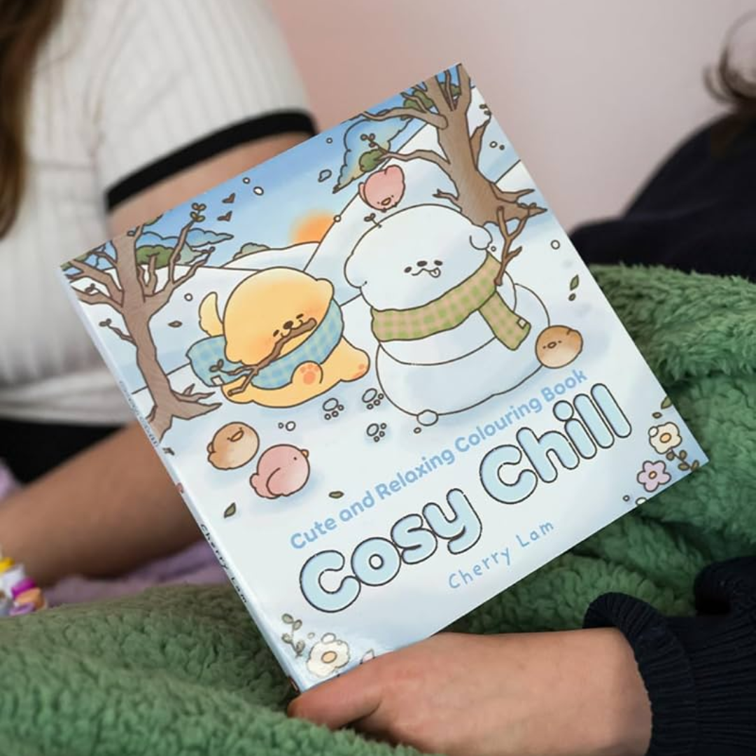 Coloring book titled 'Cosy Chill' held by a person wearing a green sweater.