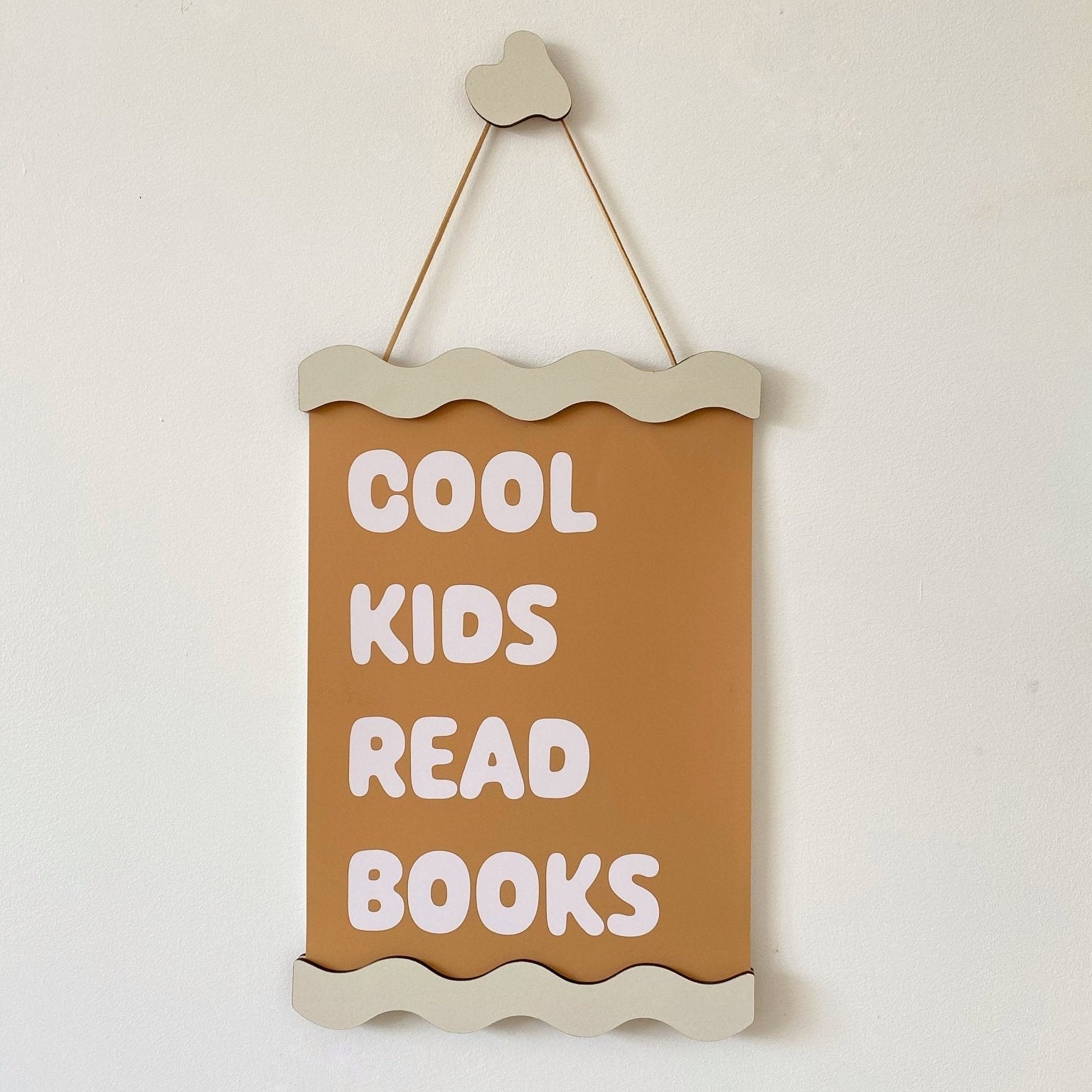 Decorative sign with 'Cool kids read books' text on a plain background
