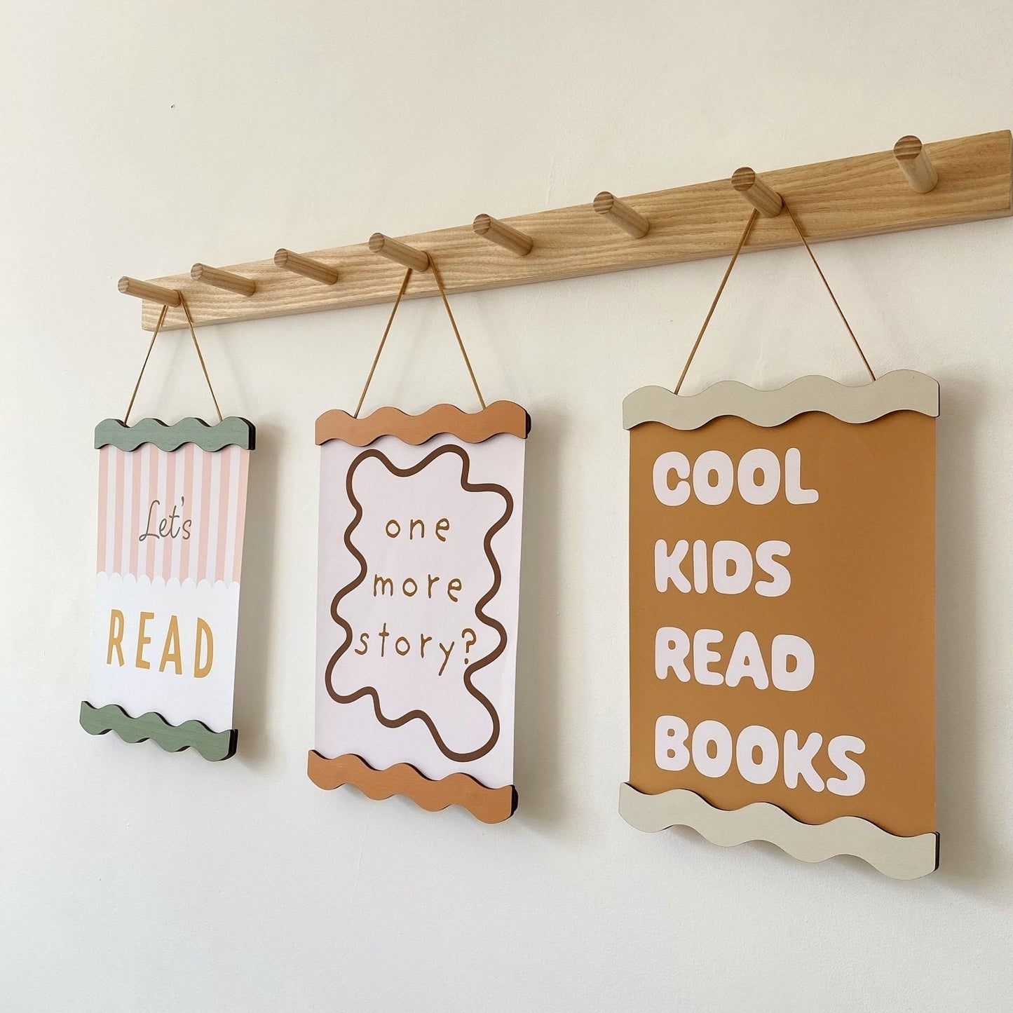 Three motivational signs for children hanging on a wooden rod against a white wall.