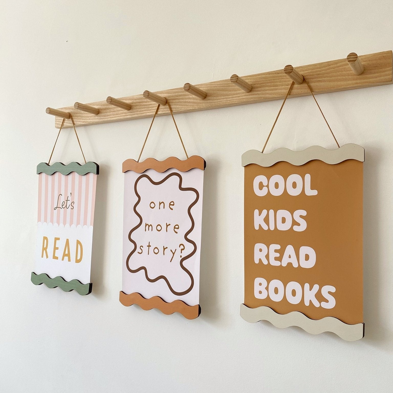 Three motivational signs for children hanging on a wooden rod against a white wall.