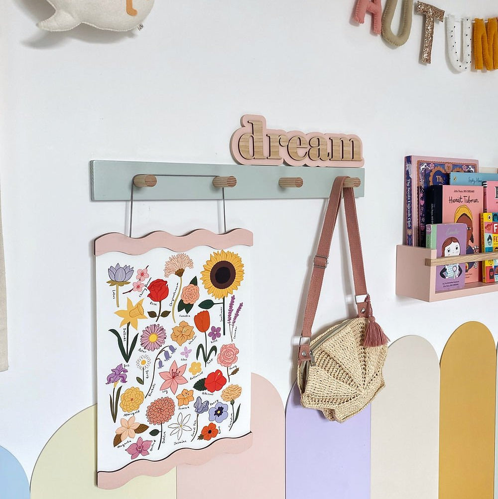 Children's room decor with a floral poster, 'hello' sign, and 'dream' wall hook.