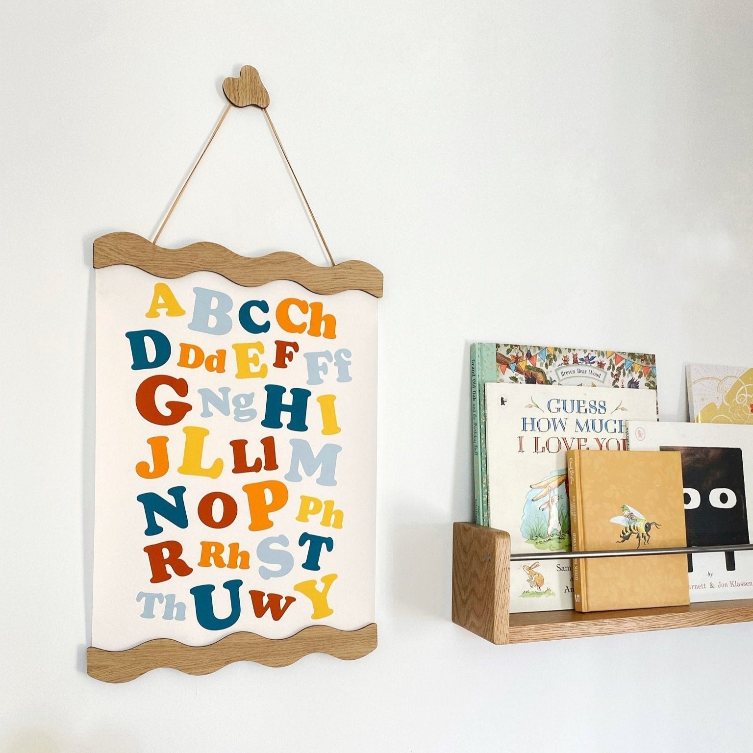Children's alphabet poster hanging on a wall with books below